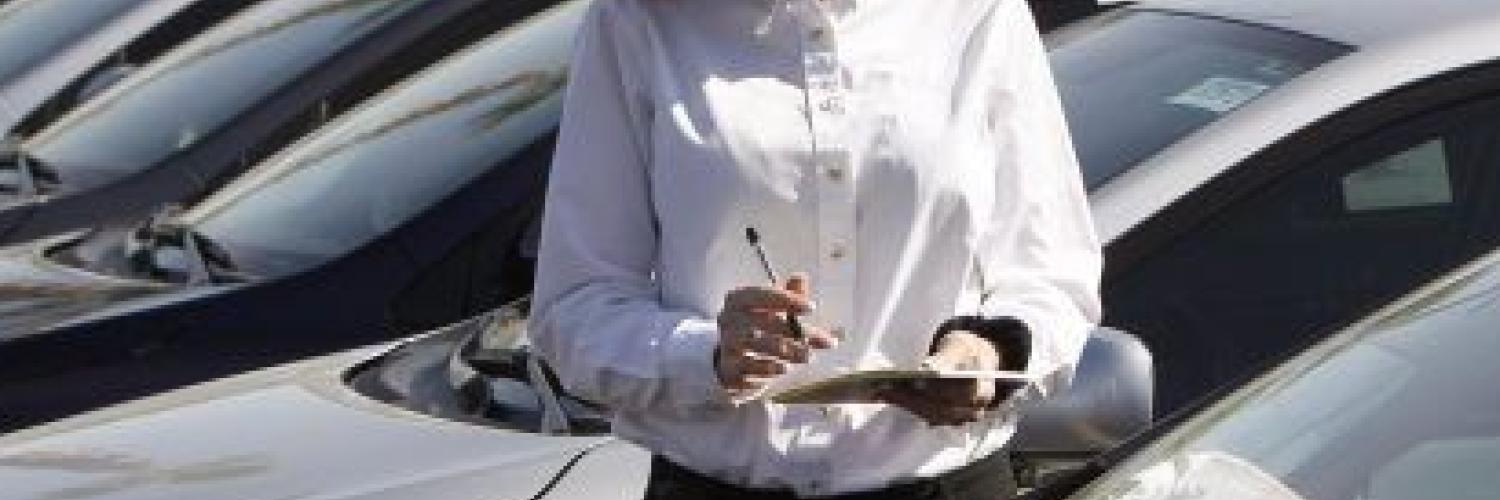 A woman standing next to a car, holding a clipboard
