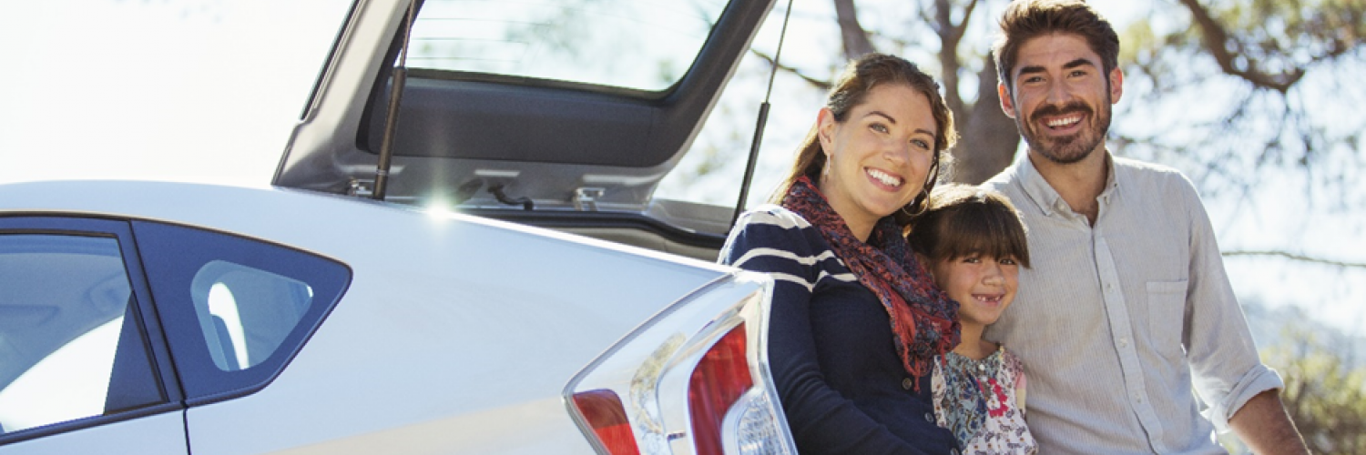 A family smiling at the back of their car