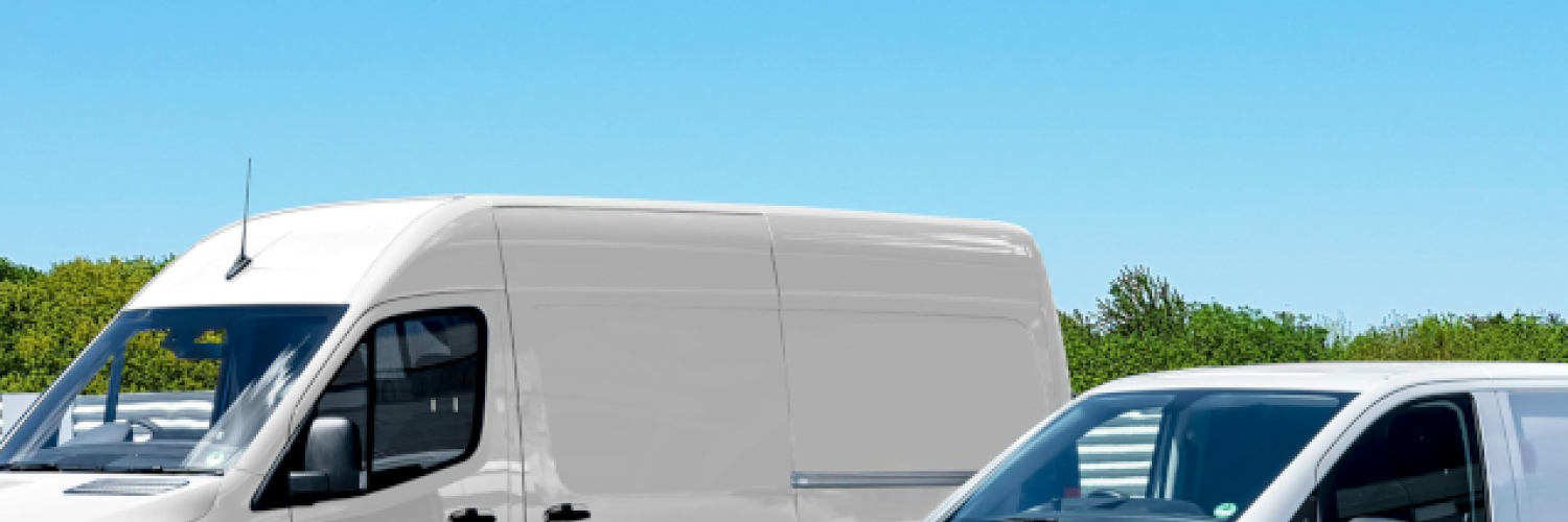 Two white eLCVs standing next to each other in a parking lot with a clear blue sky in the background