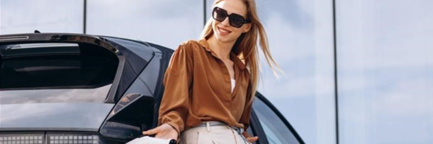 A woman standing against a BEV while charging