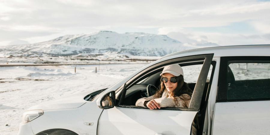 A woman sitting in a white car in a snowy landscape