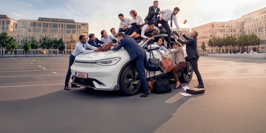 A whole team surrounding a small car on a parking lot