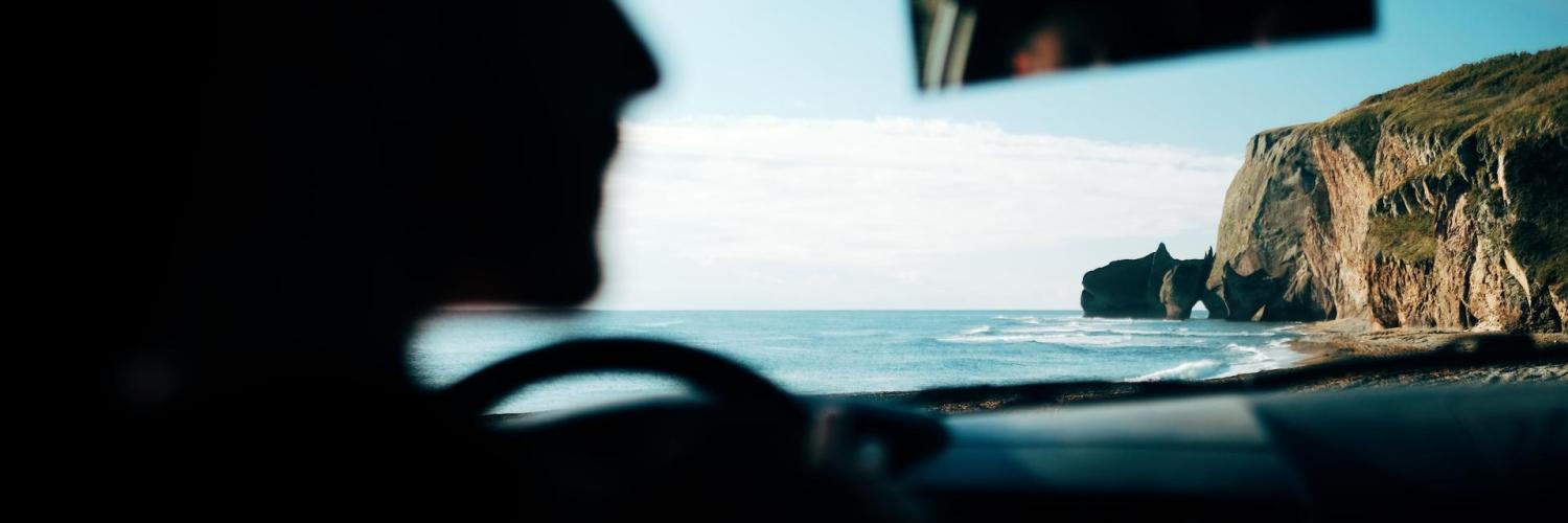 person in car driving by the seaside