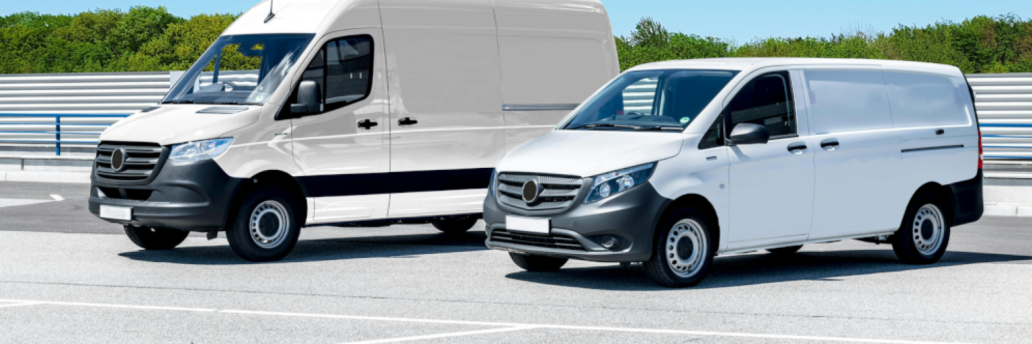 Two white eLCVs standing next to each other in a parking lot with a clear blue sky in the background