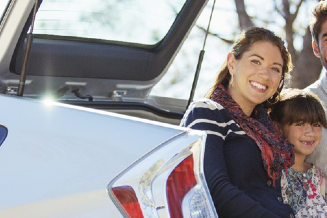 A family smiling at the back of their car A family smiling at the back of their car