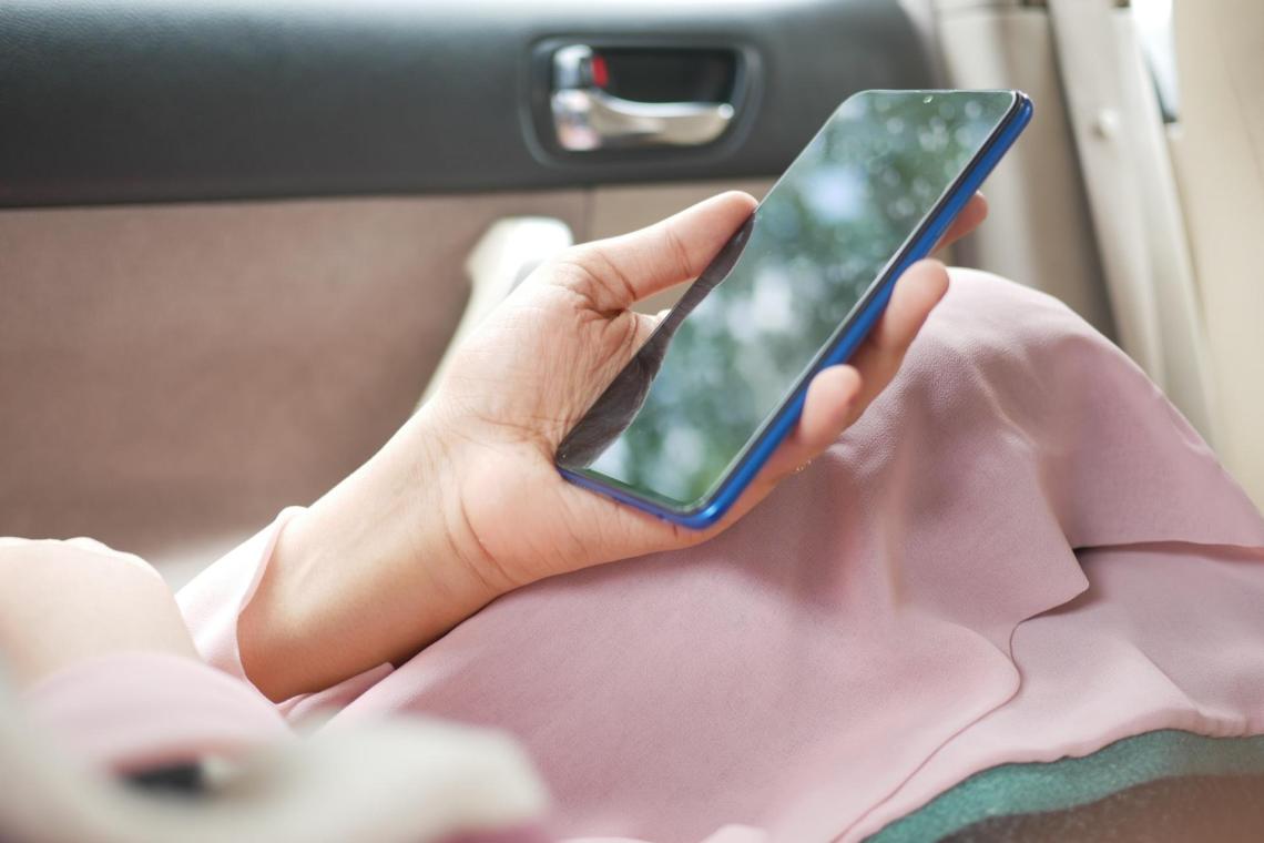 woman holding a smartphone in her car