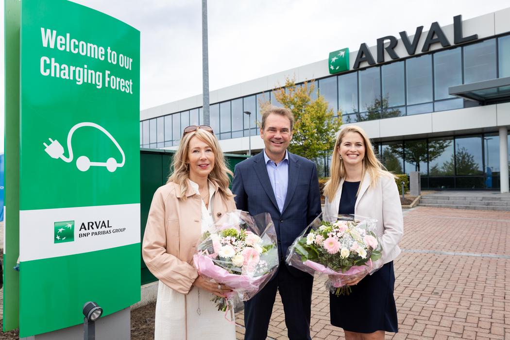 An De Pauw, Laurent Loncke, and Evi Van der Plas standing next to the "Welcome to our Charging Forest" totem